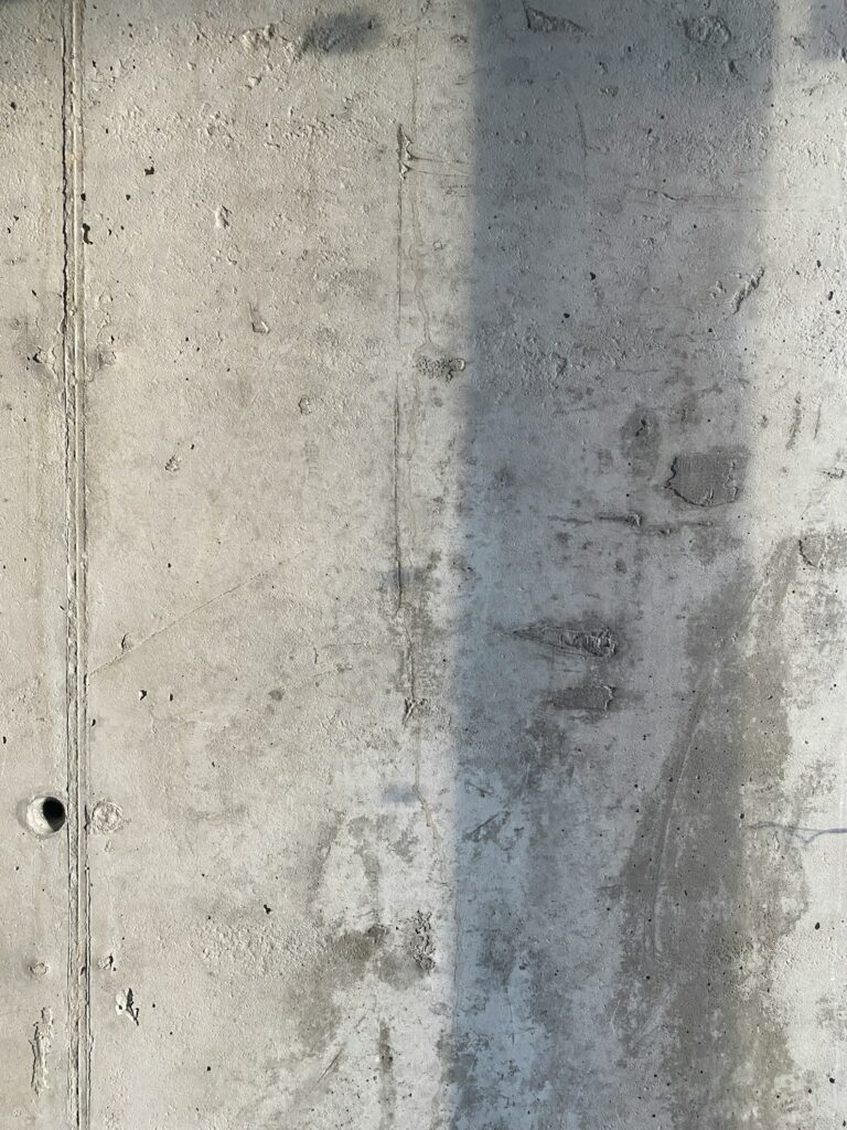 A homeowner fills a narrow crack in a concrete driveway with a trowel and crack filler.