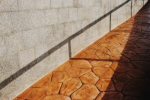 A close-up of a person sweeping a clean concrete patio with a broom on a sunny day.