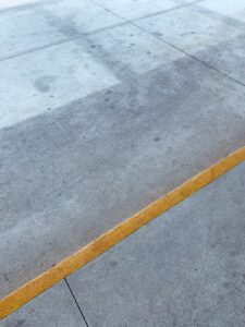 A close view of a residential concrete driveway showing cracks and surface discoloration.