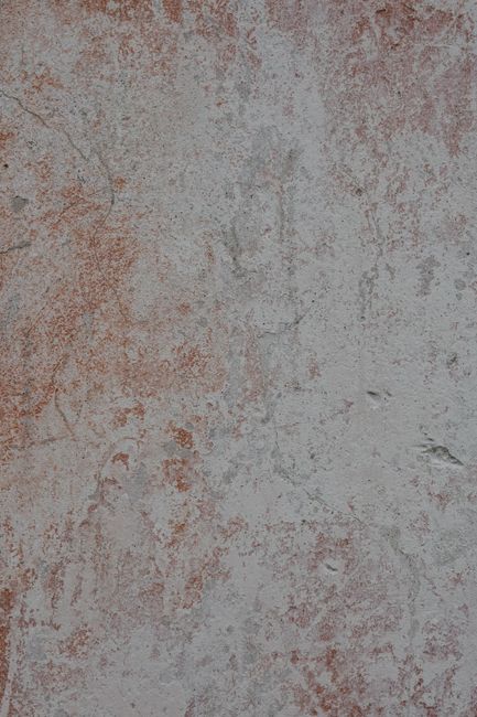 Person scrubbing a dark oil stain from a concrete driveway with a stiff brush and cleaning solution.