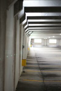 A homeowner inspects small cracks on a clean concrete garage floor with a flashlight.
