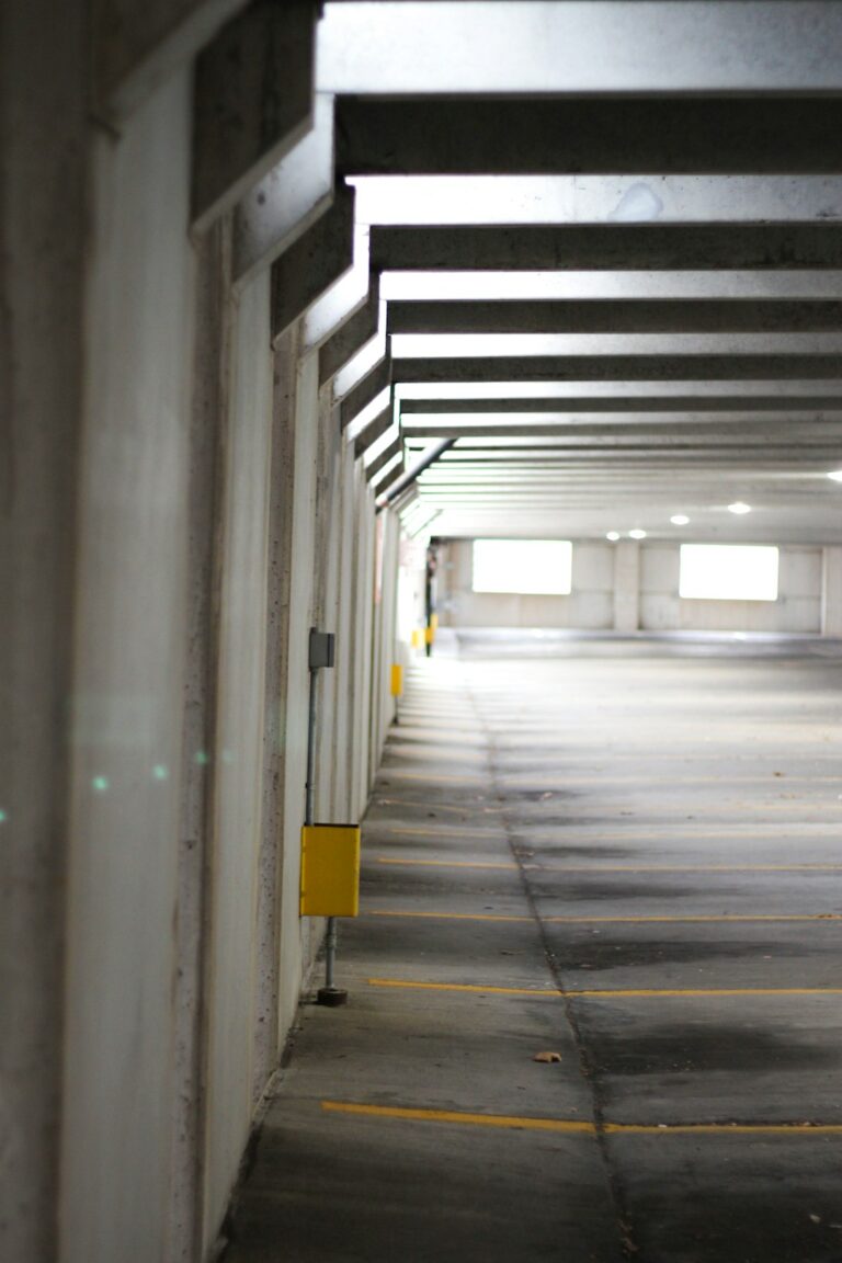 A homeowner inspects small cracks on a clean concrete garage floor with a flashlight.